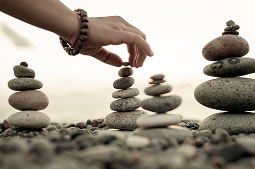 hand placing rock on top of Zen rock stack